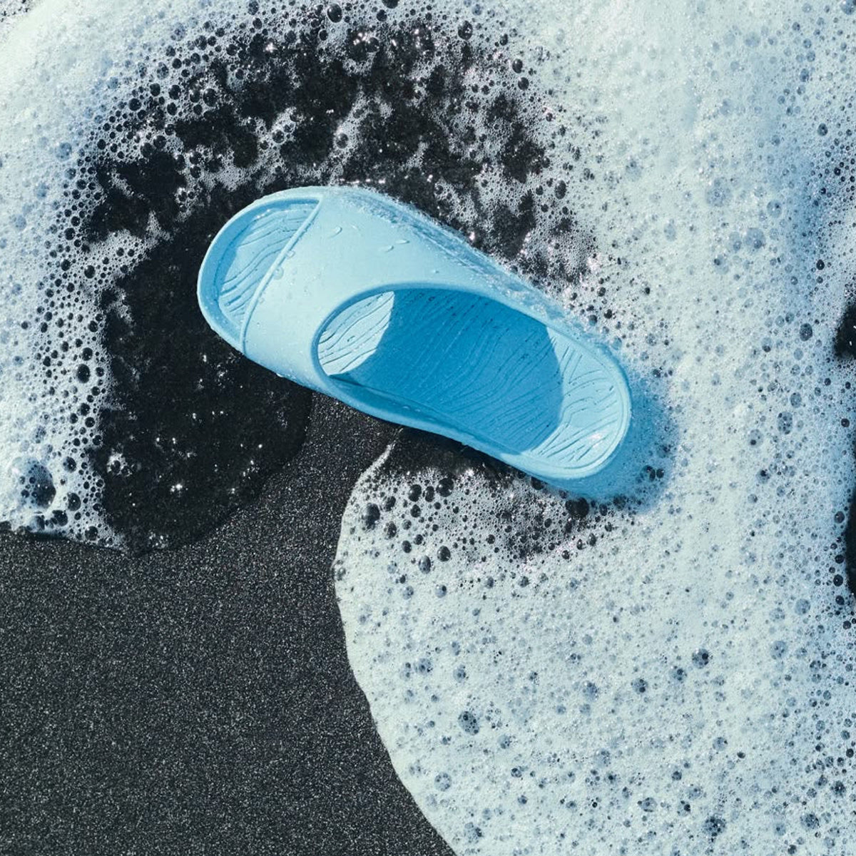 norda 008 Slide Kanagawa top view on beach with waves washing over showing textured footbed and Vibram ECOSTEP traction in wet conditions