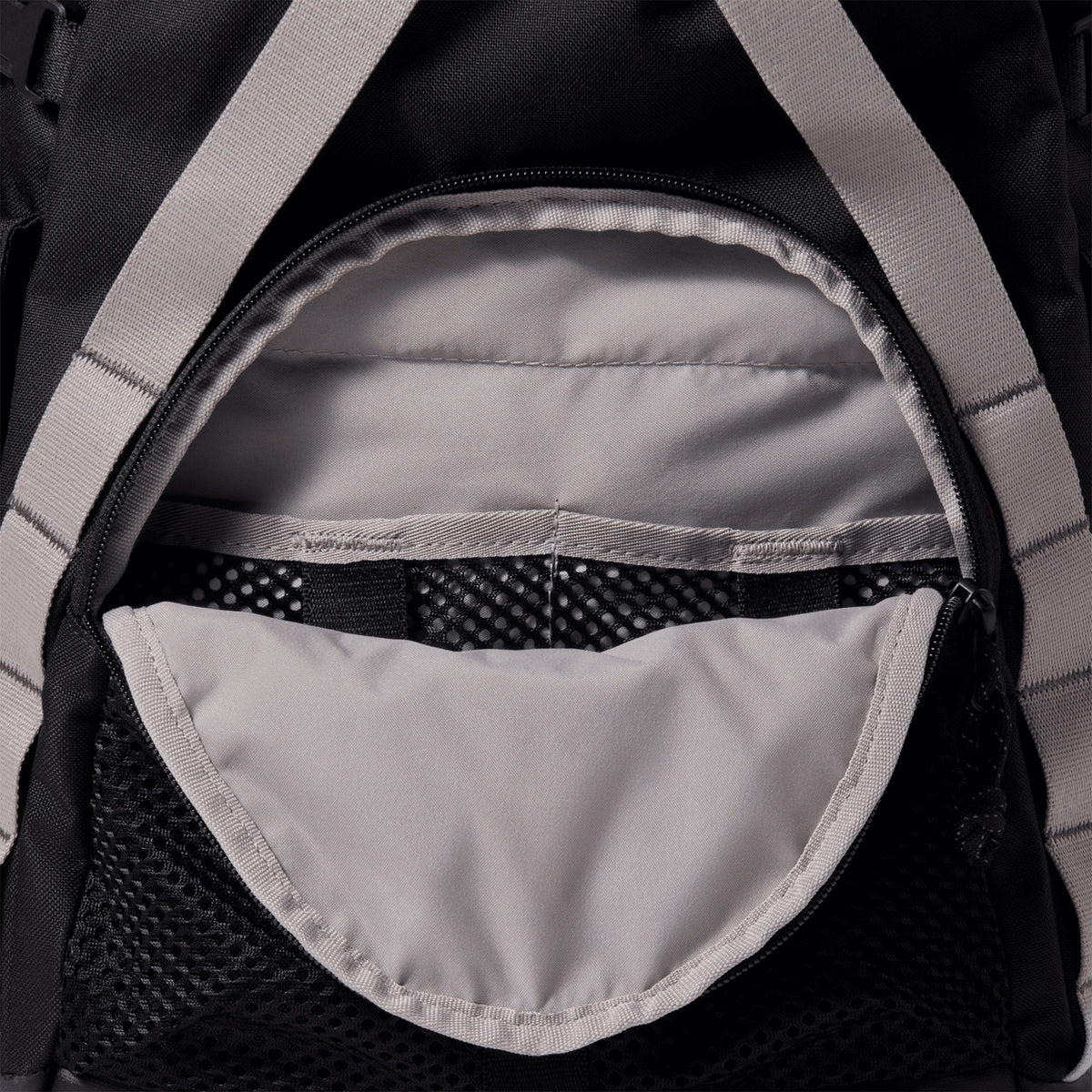 Close-up of an open Nike ACG Daymax 25L Backpack in Black / College Grey, highlighting the light grey interior fabric, multiple inner compartments, and black mesh sections for organization.
