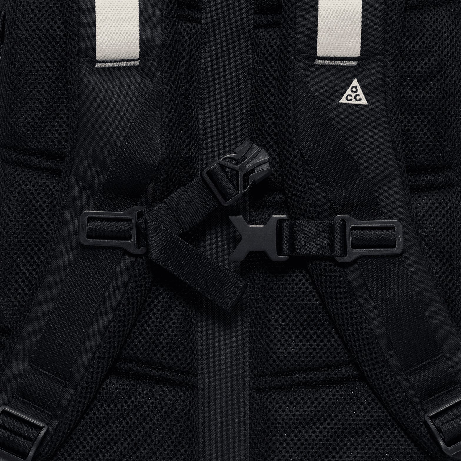 Close-up of the Nike ACG Daymax 25L Backpack in Black / College Grey, showcasing mesh padding, adjustable straps with a plastic buckle, and a small white triangle ACG logo on one strap—an adventure-ready backpack engineered for comfort and durability.