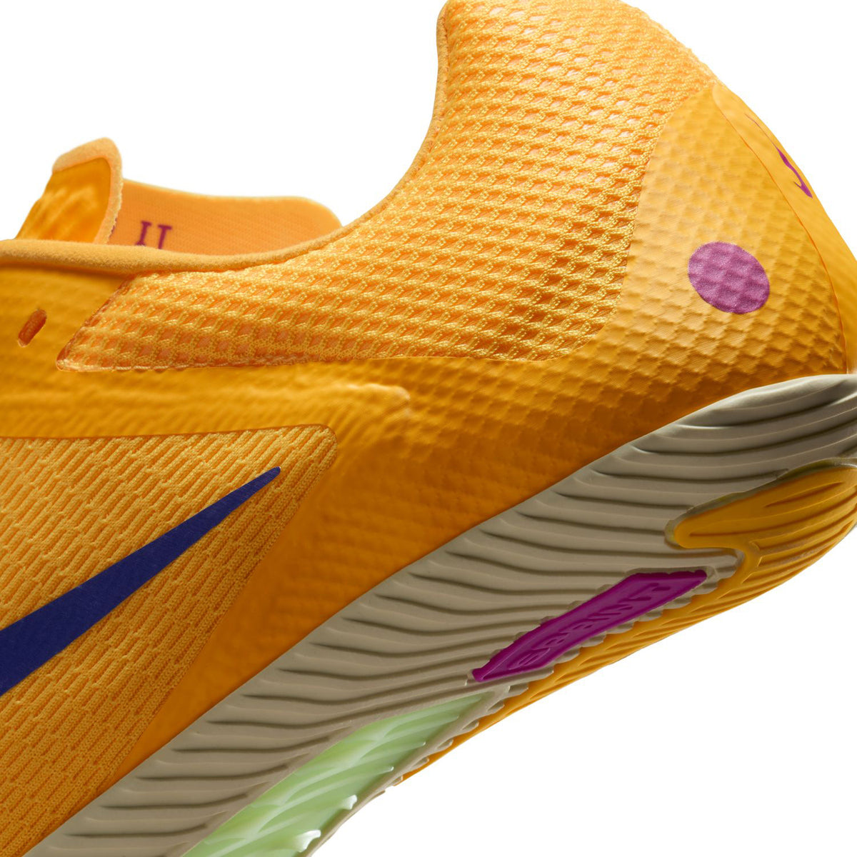 Close-up of an orange athletic shoe with a textured upper, purple dot detail, blue swoosh, and light-colored sole featuring purple and green accents.