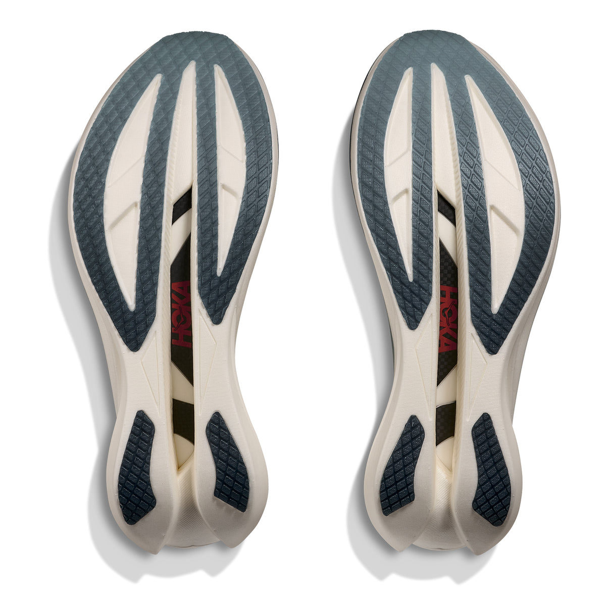 A pair of Hoka Cielo X1 3.0 Running Shoes in Alabaster / Yellow Gold, shown with their mostly white soles featuring dark blue textured sections, black cutouts, and the word “HOKA” in red on the left sole; these carbon racing shoes feature a responsive PEBA midsole. The soles are facing up against a white background.