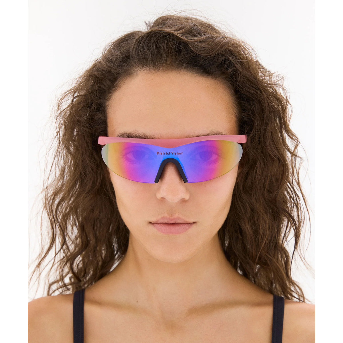 District Vision Koharu Eclipse in Desert Rose D+ Aqua Mirror — worn on female model showing six-base frame fit, desert rose colourway and D+ Aqua Mirror lens in natural light
