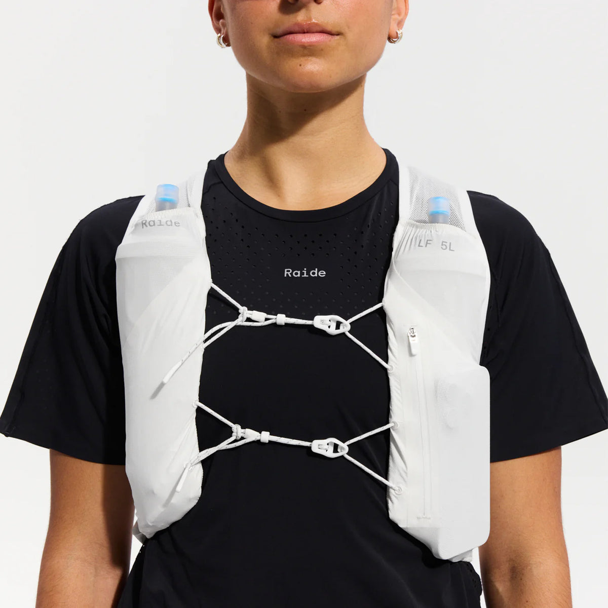 Raide LF 5L Running Vest in White — front view worn on model showing chest tension system, integrated pole quiver placement and white DyneemaⓇ mesh base with secure fit demonstration