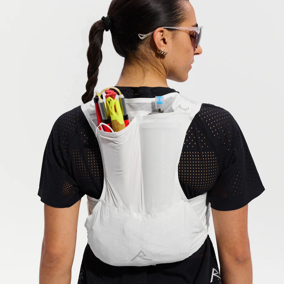 Raide LF 5L Running Vest in White — back view worn on model showing rear hydration carry, integrated ice tool carry construction and white DyneemaⓇ mesh locking loops in motion