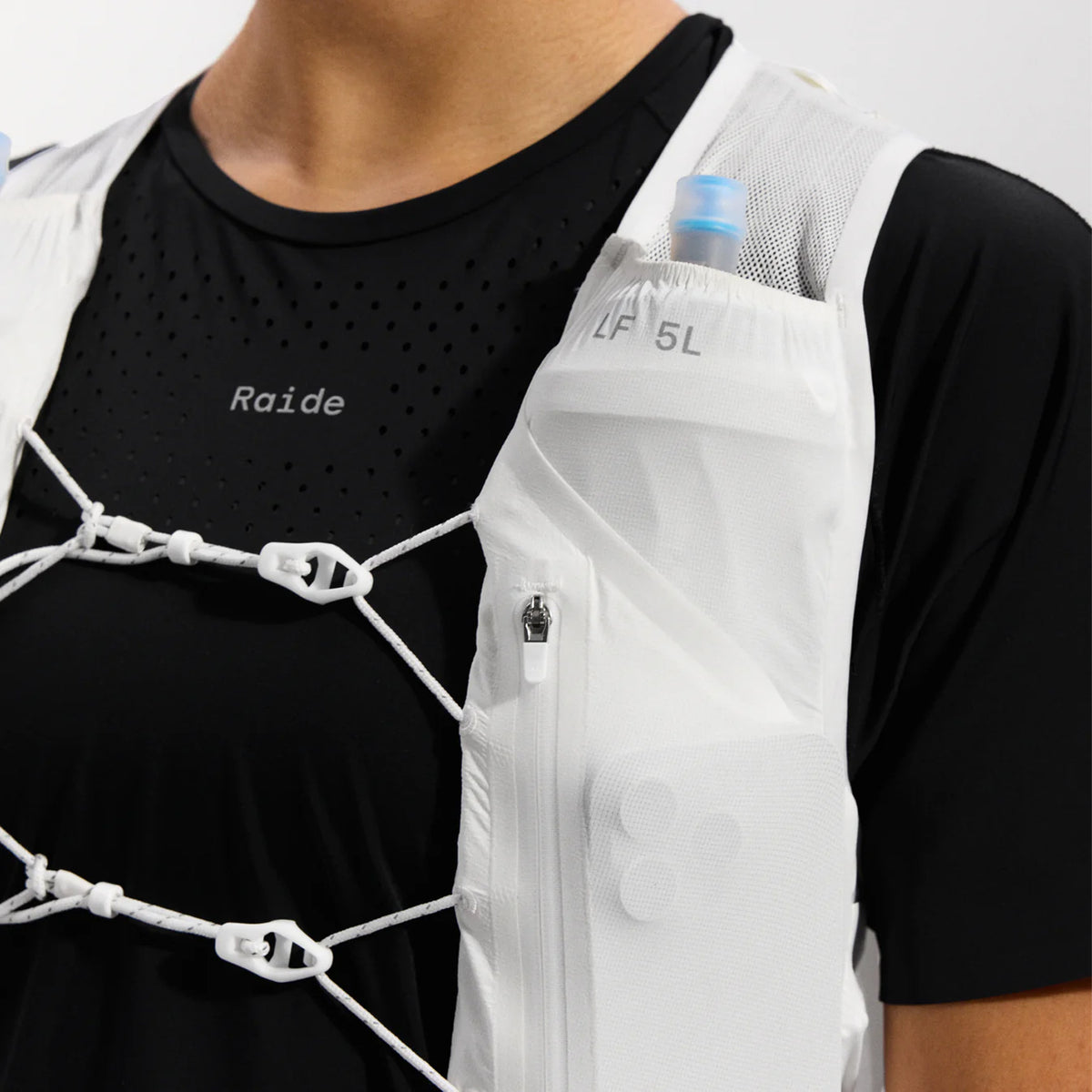 Raide LF 5L Running Vest in White — closeup showing chest tension system detail, zipped phone storage pocket with key loop and integrated whistle on white DotAir body fabric
