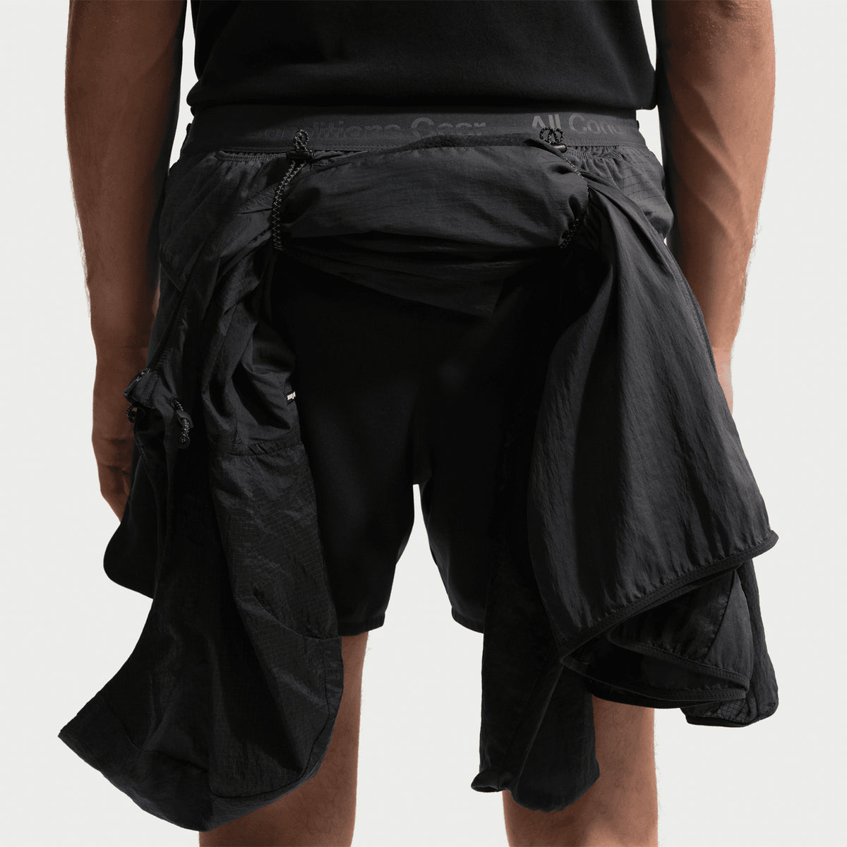 Men's Nike ACG Second Sunrise Dri-FIT 5 Inch Running Shorts Black Anthracite Summit White back view showing jacket looped through back loops designed for trekking poles or gear storage during trail running and hiking
