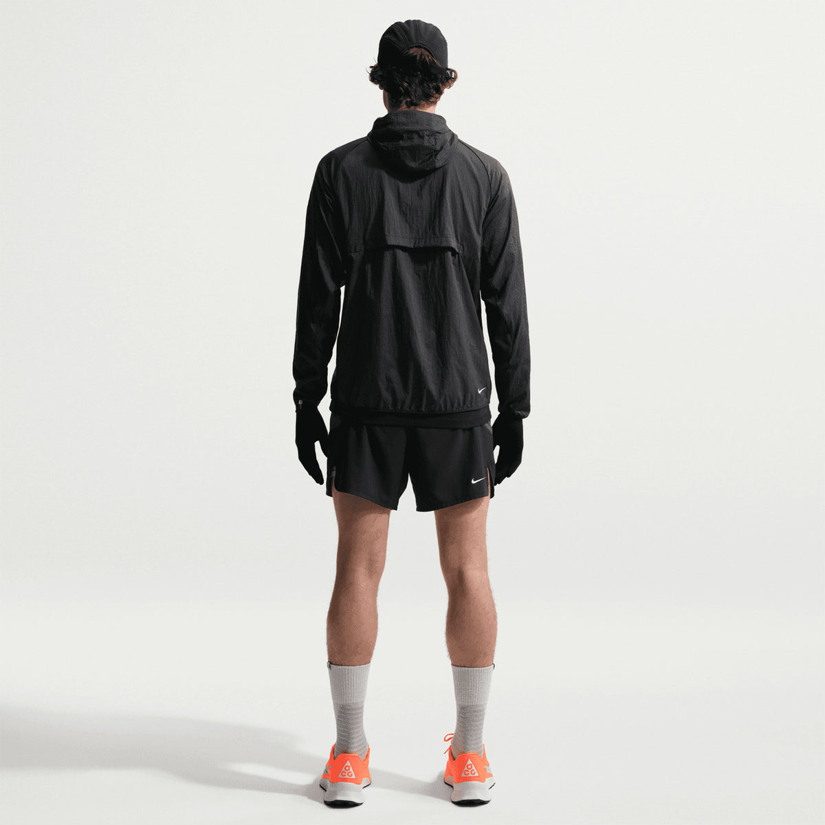 Men's Nike ACG Second Sunrise Dri-FIT 5 Inch Running Shorts Black Anthracite Summit White full body back view on male trail runner showing zippered phone pocket, trekking pole loops and reflective ACG branding with Dri-FIT ADV construction for long-distance trails