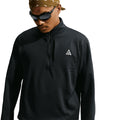 A man wearing the Nike Men’s ACG Wolf Grid 1/2 Zip Top in Black / Summit White, paired with dark sunglasses and a brown bandana, looks down. The breathable warmth of the Nike pullover stands out against the crisp white background.