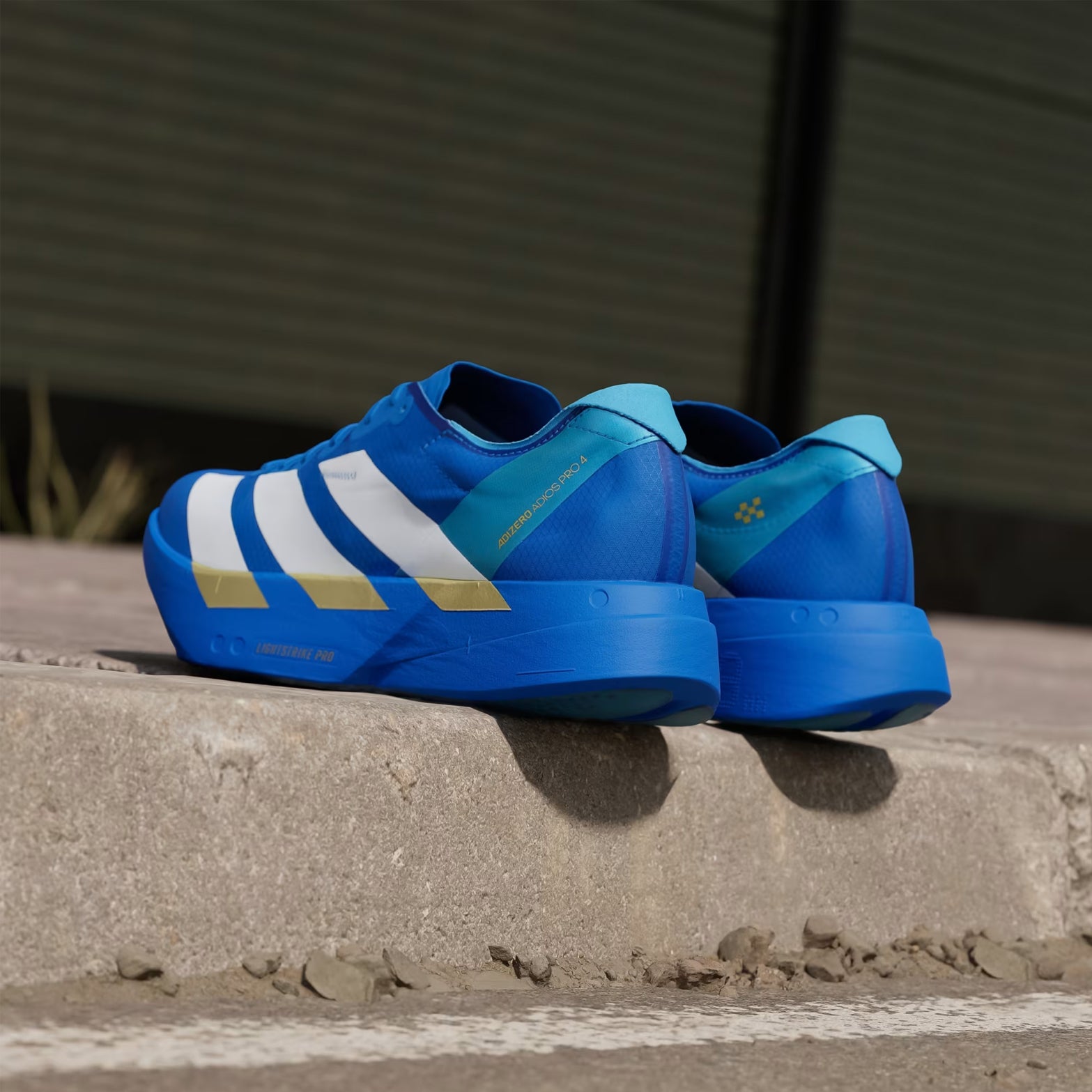 Men's adidas Adizero Adios Pro 4 Running Shoes Blue Cloud White Lime Burst angled heel view showing LIGHTSTRIKE PRO foam stack with carbon ENERGYRODS 2.0 for marathon racing performance