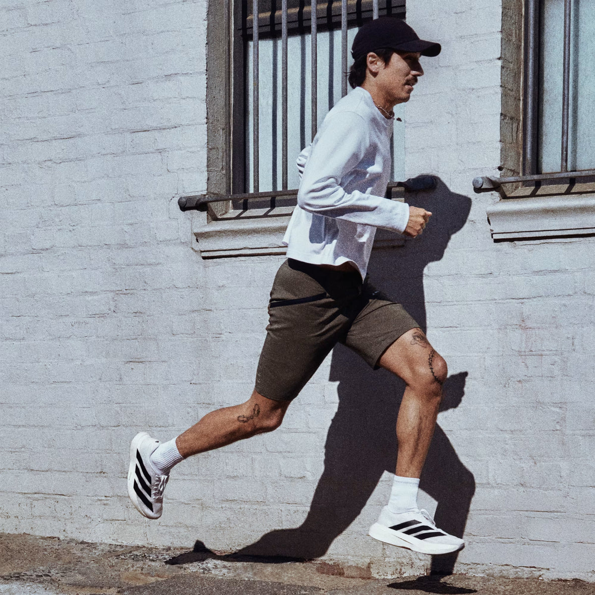 Men's adidas Adizero Evo SL Running Shoes Cloud White Core Black Cloud White worn by male runner in motion showing LIGHTSTRIKE PRO foam energy return with Continental rubber