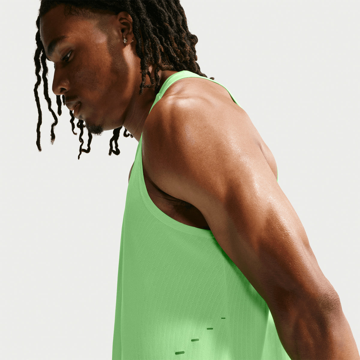 Men's Nike Aero-FIT Running Vest Volt Light Silver Reflective Silver side view on male runner showing lightweight knit construction with side hem vents and Aero-FIT mesh zones for unrestricted movement and maximum airflow during running