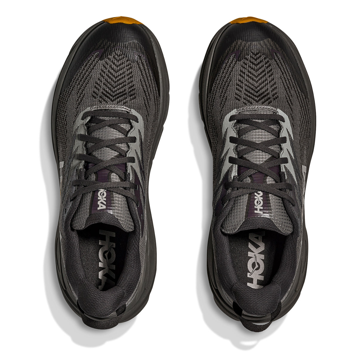 Top view of a pair of Hoka Men’s Challenger 8 GORE-TEX Trail Running Shoes in Asphalt Grey and Varsity Yellow, featuring cushioned soles, breathable mesh uppers, black laces, and yellow accents on the toe area. The Hoka logo appears on the tongue and inner sole of each shoe.