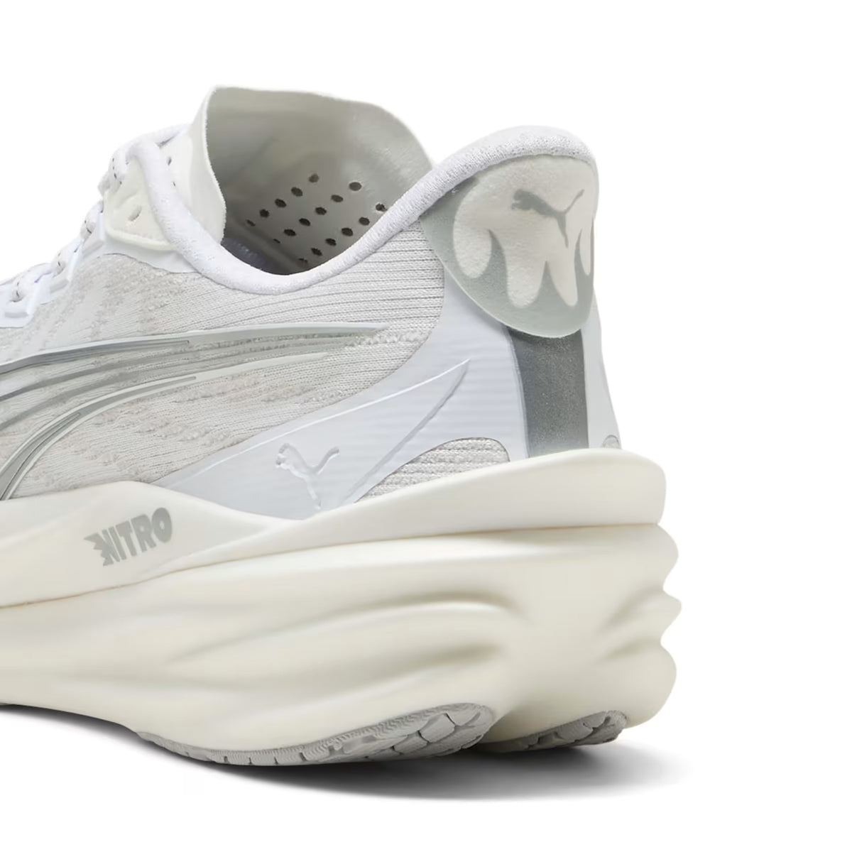Close-up view of the heel of the Men’s Deviate NITRO 4 Running Shoe by Puma in Puma White and Feather Grey, highlighting the brand logo, “NITRO” text, and a thick, textured sole designed with advanced NITROFOAM for superior cushioning in this carbon racing shoe.