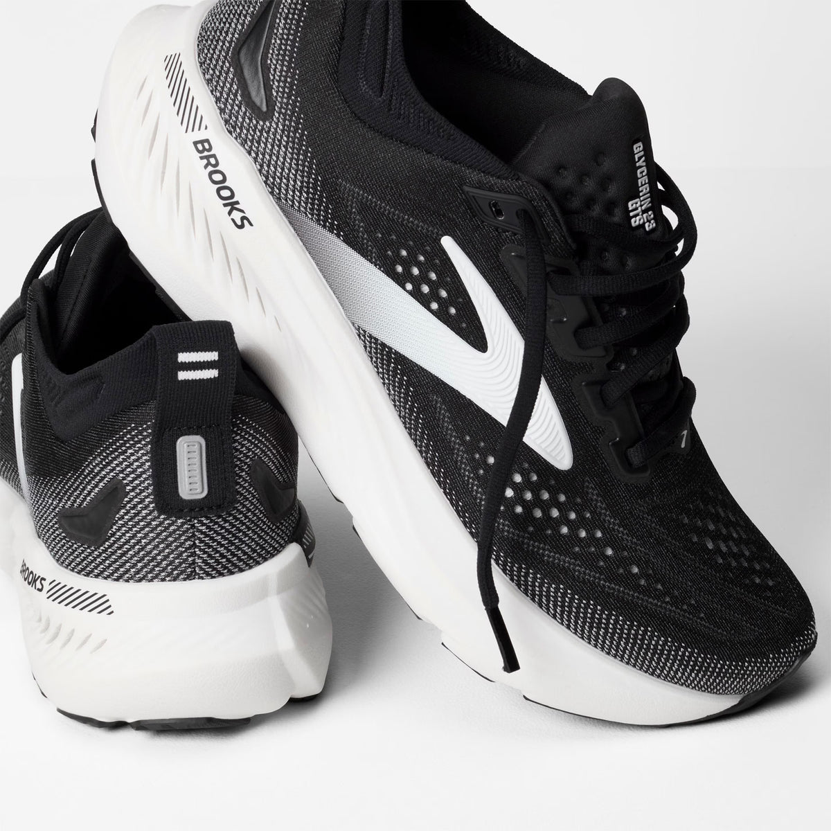 Brooks Glycerin GTS 23 men's running shoe in Black / Grey / White — angled side view showing black engineered knit upper, GuideRails support sidewalls and grey DNA TUNED cushioning midsole stack with 8mm offset profile