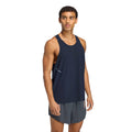 A person wearing a Men’s Hermanos Koumori Running Tank Night Navy with a small logo and patterned ventilation holes on the side, paired with grey athletic shorts.