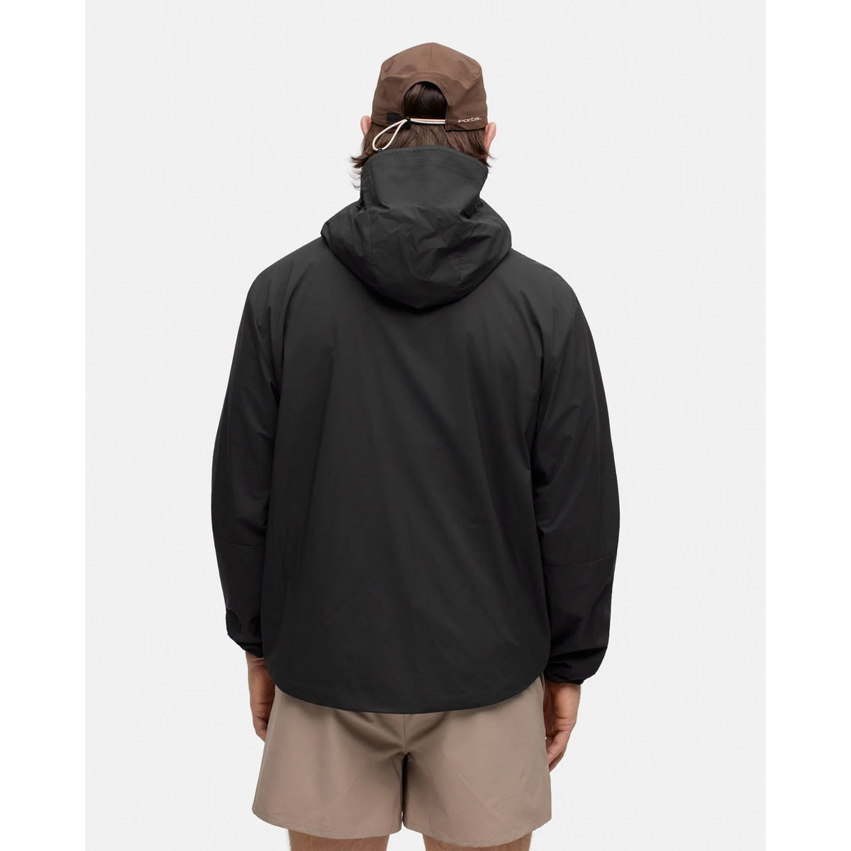 Back view of a person wearing a black Portal Men’s Level Alpha Jacket Black Beauty and tan shorts.