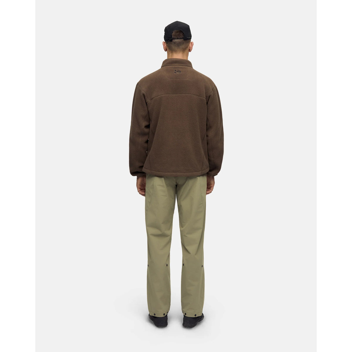 A person seen from behind wearing a brown Men’s Loam Fleece Jacket Slate Black and olive green trousers.