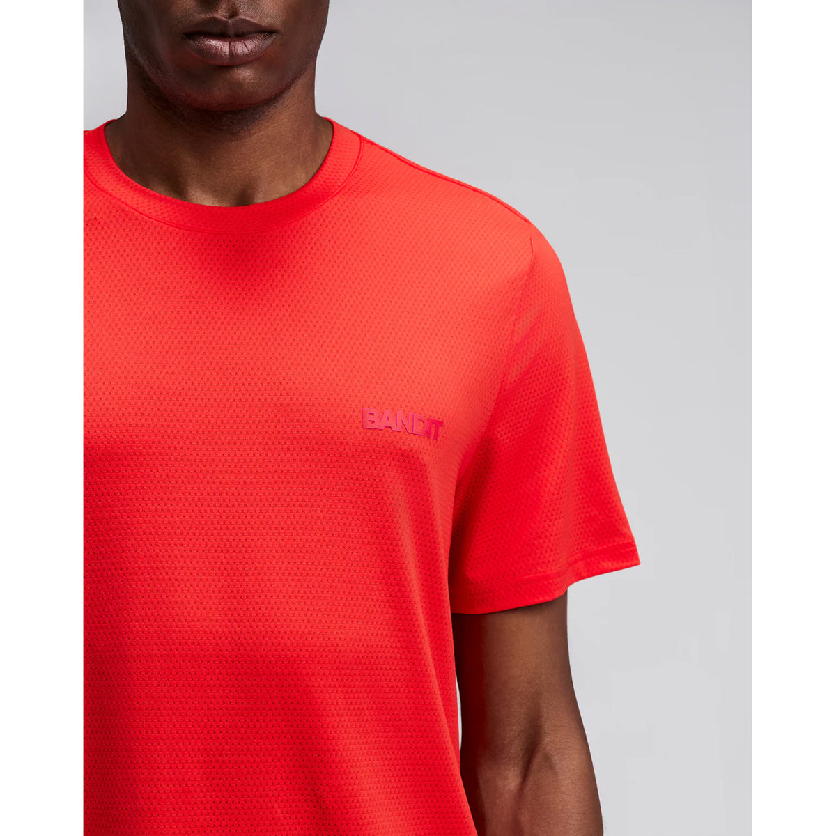 Men's Bandit Micromesh Run Tee Poppy close-up of front showing subtle two-tone Bandit logo branding with ultra-breathable Micromesh fabric and Oeko-Tex certified BPA-free construction