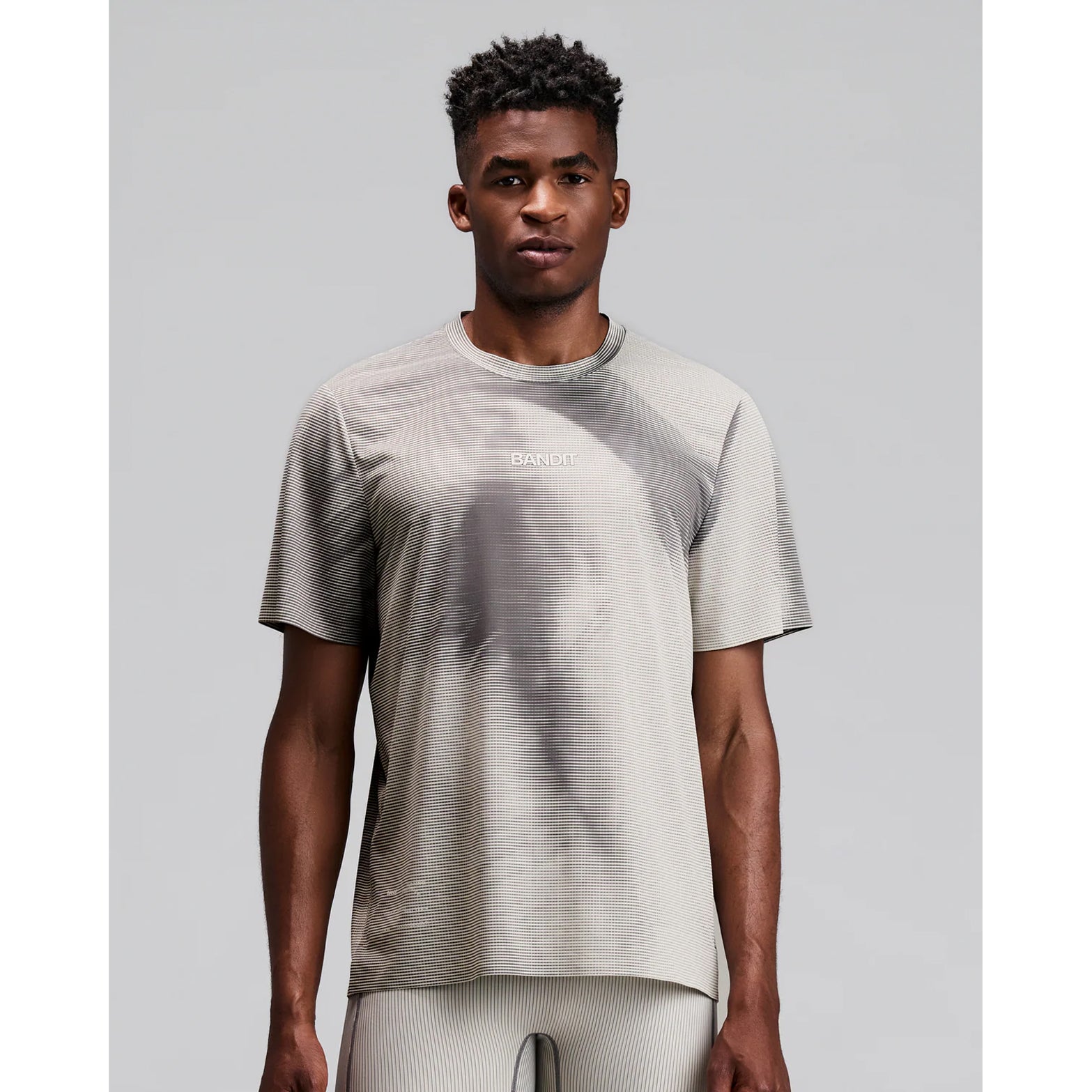 Men's Bandit Specter Performance Tee Slate Plaster front view on male runner showing relaxed fit with Specter premium sweat-wicking fabric and reflective centre front graphic for running and training
