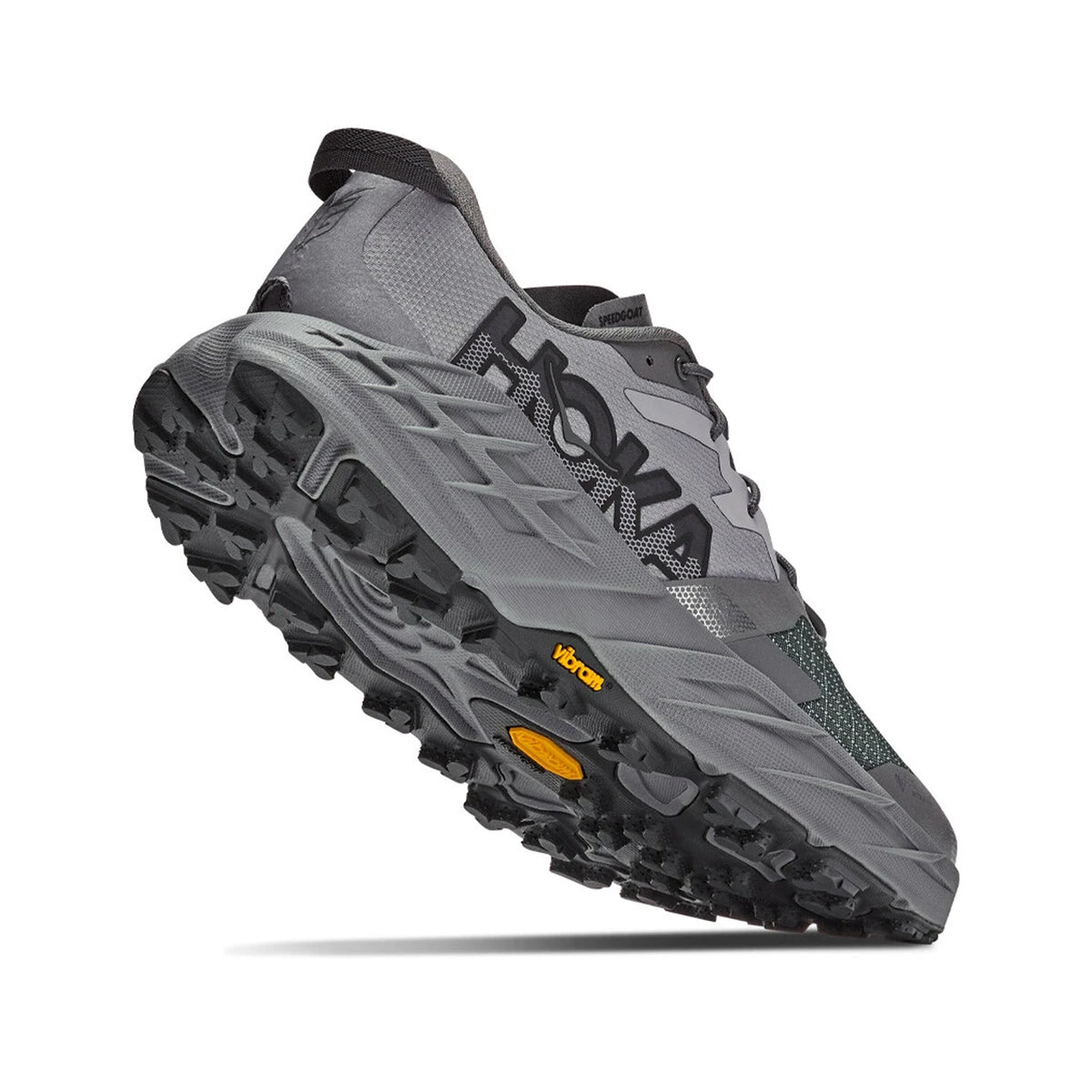 Gray Hoka running shoe shown from a low rear angle, highlighting its textured, rugged sole with yellow details and mesh upper material.