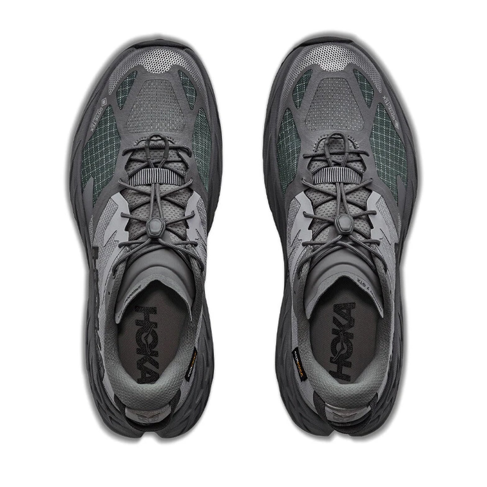 Top view of a pair of Hoka Men’s Speedgoat 7 GORE-TEX Trail Running Shoes in Asteroid / Galactic Grey, featuring grid-patterned mesh uppers, toggle laces, and black Hoka logos on the insoles, displayed side by side on a white background.