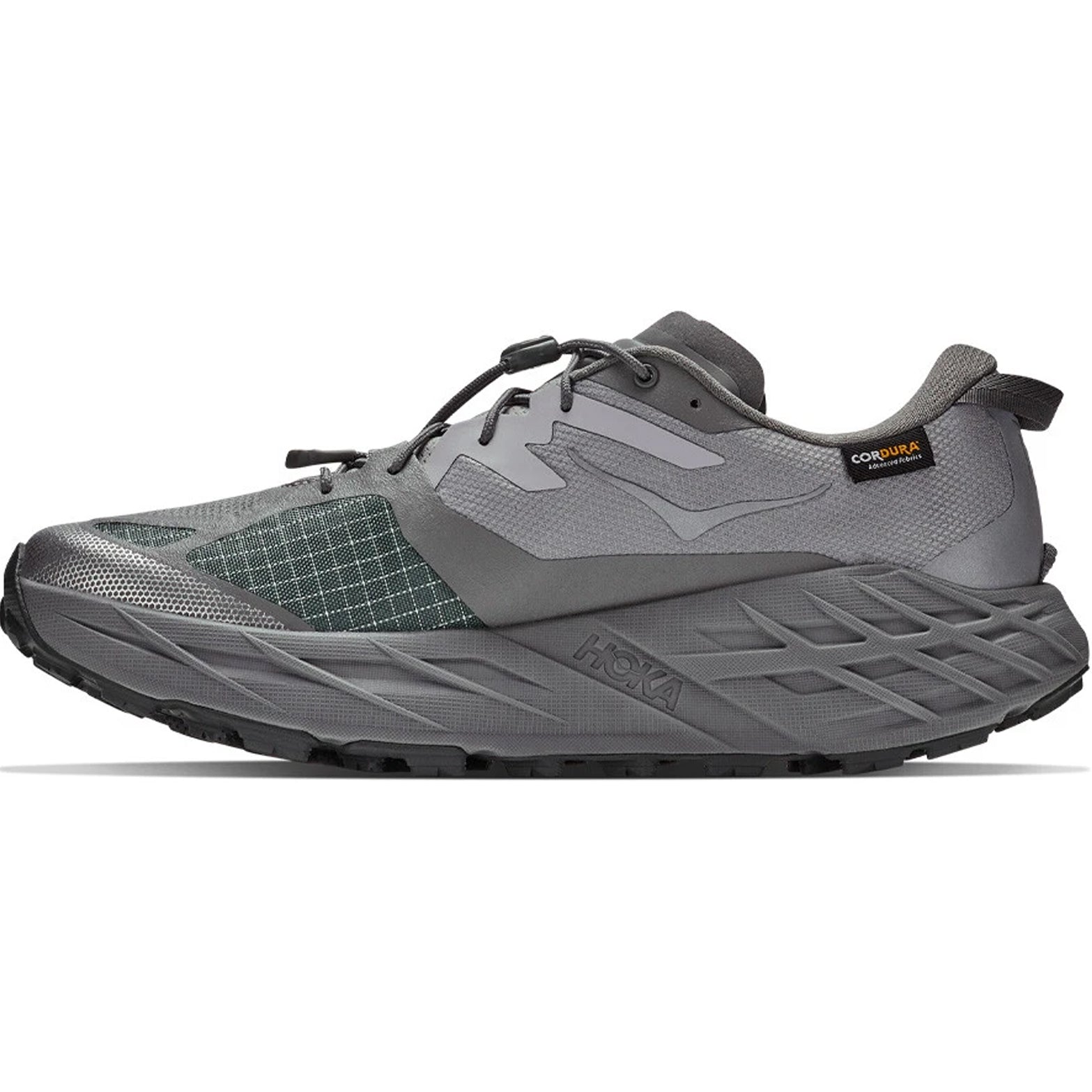 A side view of the Hoka Men’s Speedgoat 7 GORE-TEX Trail Running Shoe in Asteroid / Galactic Grey is displayed on a white background, showcasing its thick, textured sole, mesh and synthetic upper, Speedgoat logo, and Cordura tag. This waterproof trail running shoe is built for durability and comfort on rugged terrain.