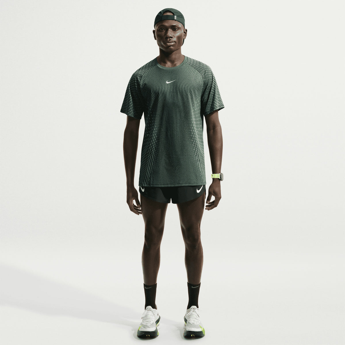 Men's Nike Stride Aero-FIT Running Tee Black Light Green Spark full body view on male runner showing lightweight knit with strategic mesh zones and side hem vents for maximum breathability and unrestricted movement