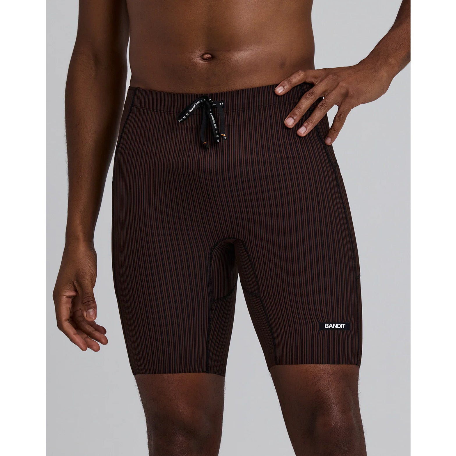 Bandit Striped Cadence 7 Pocket Half Tights men's in Cacao / Black — front view worn on model showing compression fit, cacao and black ribbed knit and double-layered front fabric in motion