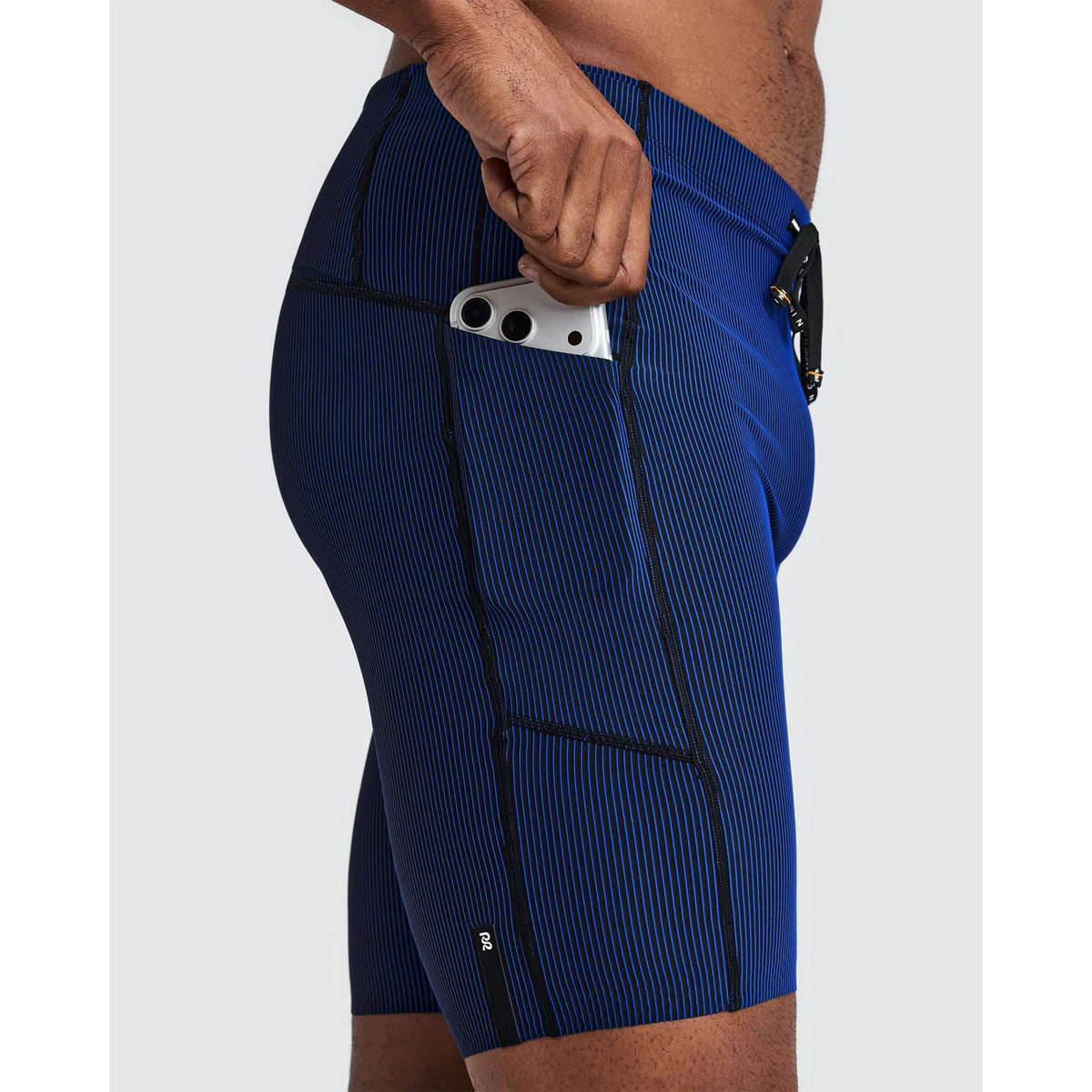 Side view of Bandit Men’s Striped Cadence Half Tights Black / Bauhaus Blue, featuring blue and black striped ribbed compression fabric with a smartphone tucked into a side pocket.