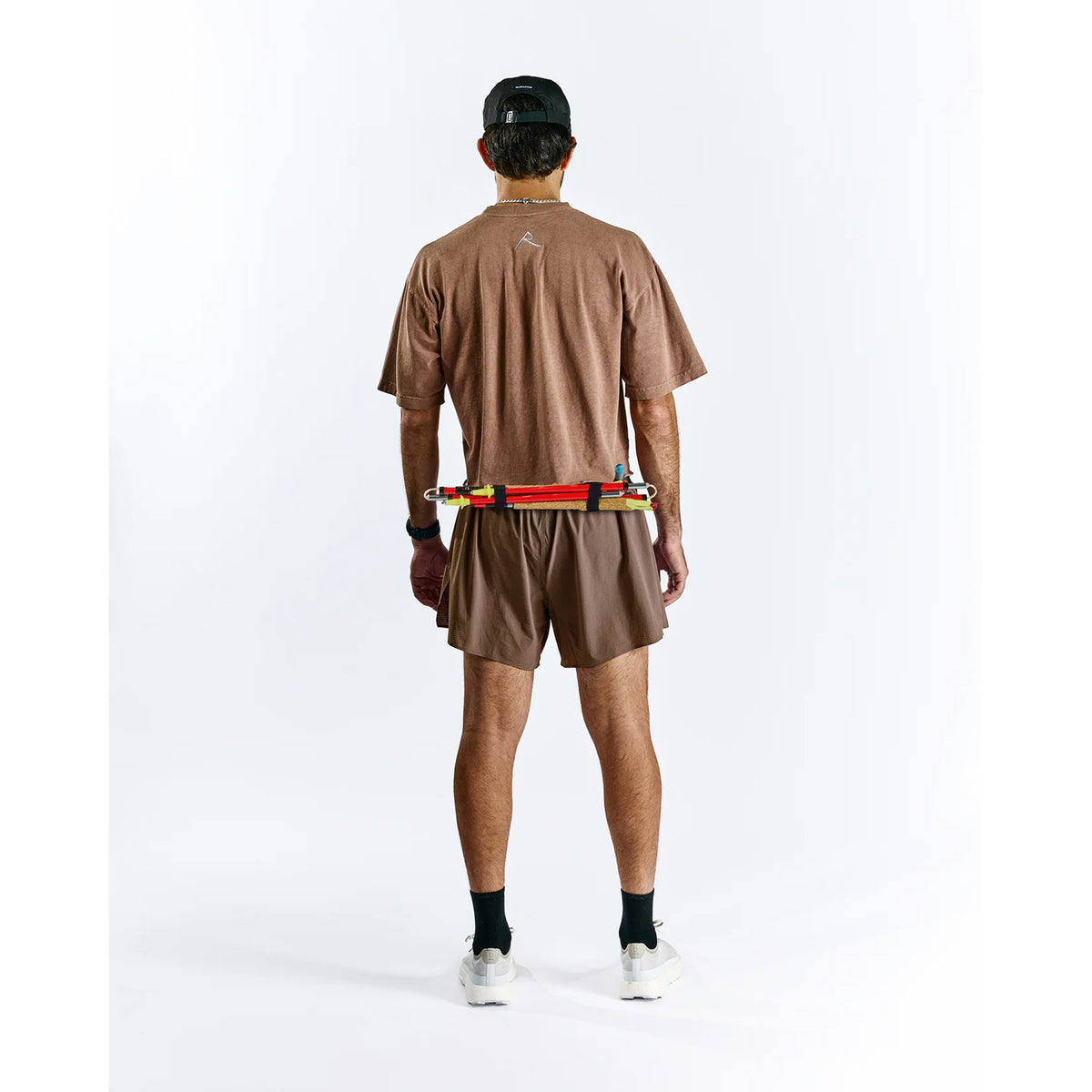 Raide TrailTech Short men's in Bark — full body back view worn on model showing large rear pocket placement, zippered pocket detail and Toray DotAir outer construction in motion on trail