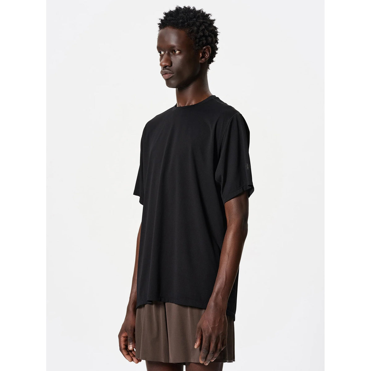 Goldwin Men's WF-Dry Tee Black side view on male runner showing forearm wedges for mobility and backpack-compatible raglan sleeve design