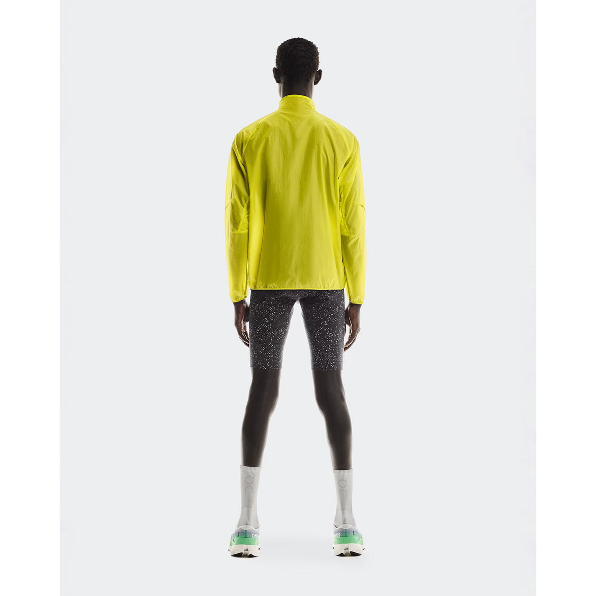 Men's On Zero Jacket Lime full body back view on male runner showing breathable lightweight construction with reflective elements for low-light visibility