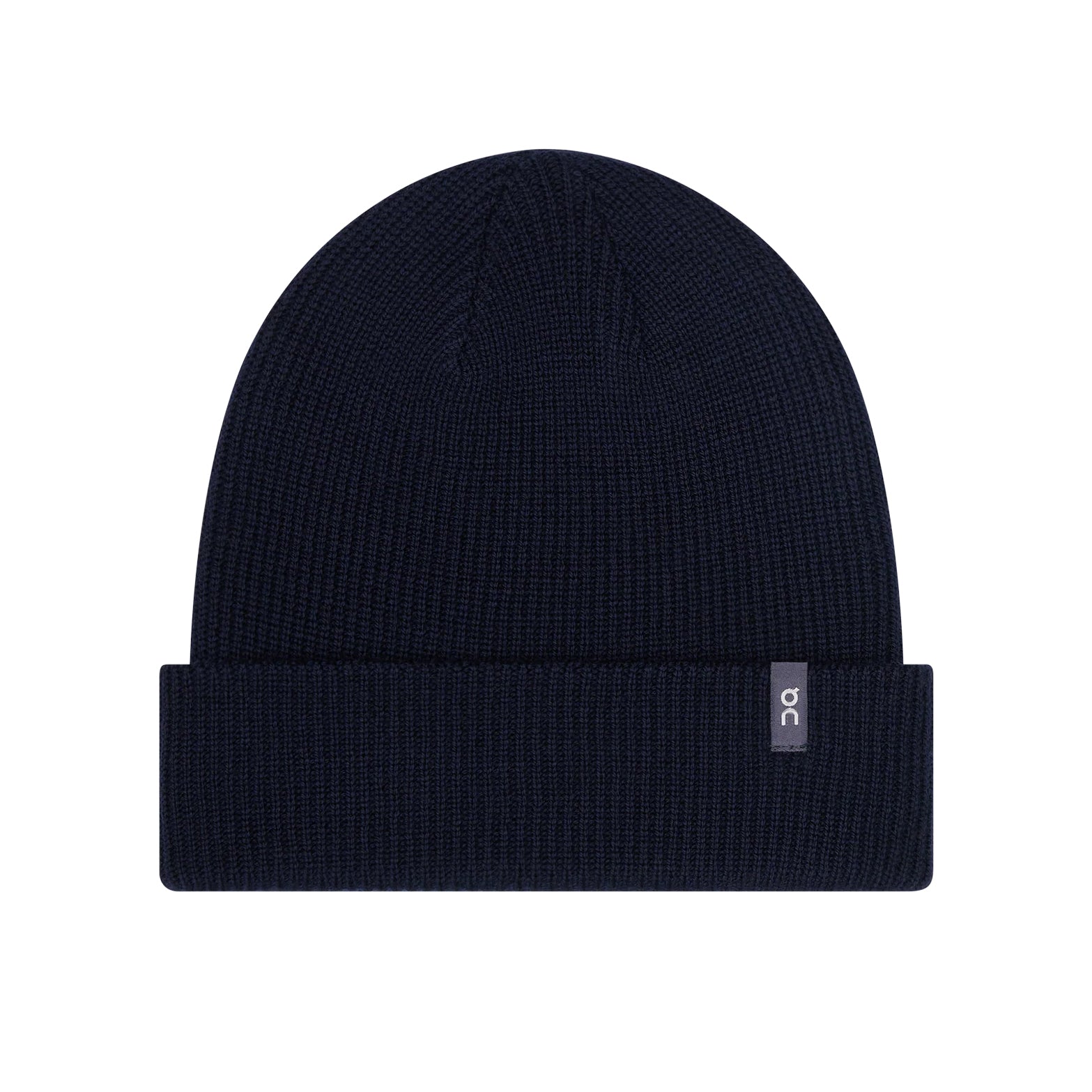 The Merino Beanie Midnight by On is a black knit beanie crafted from temperature-regulating Merino wool, featuring a folded brim and a small rectangular “oc” tag on the front—perfect for everyday wear or as your go-to running beanie.