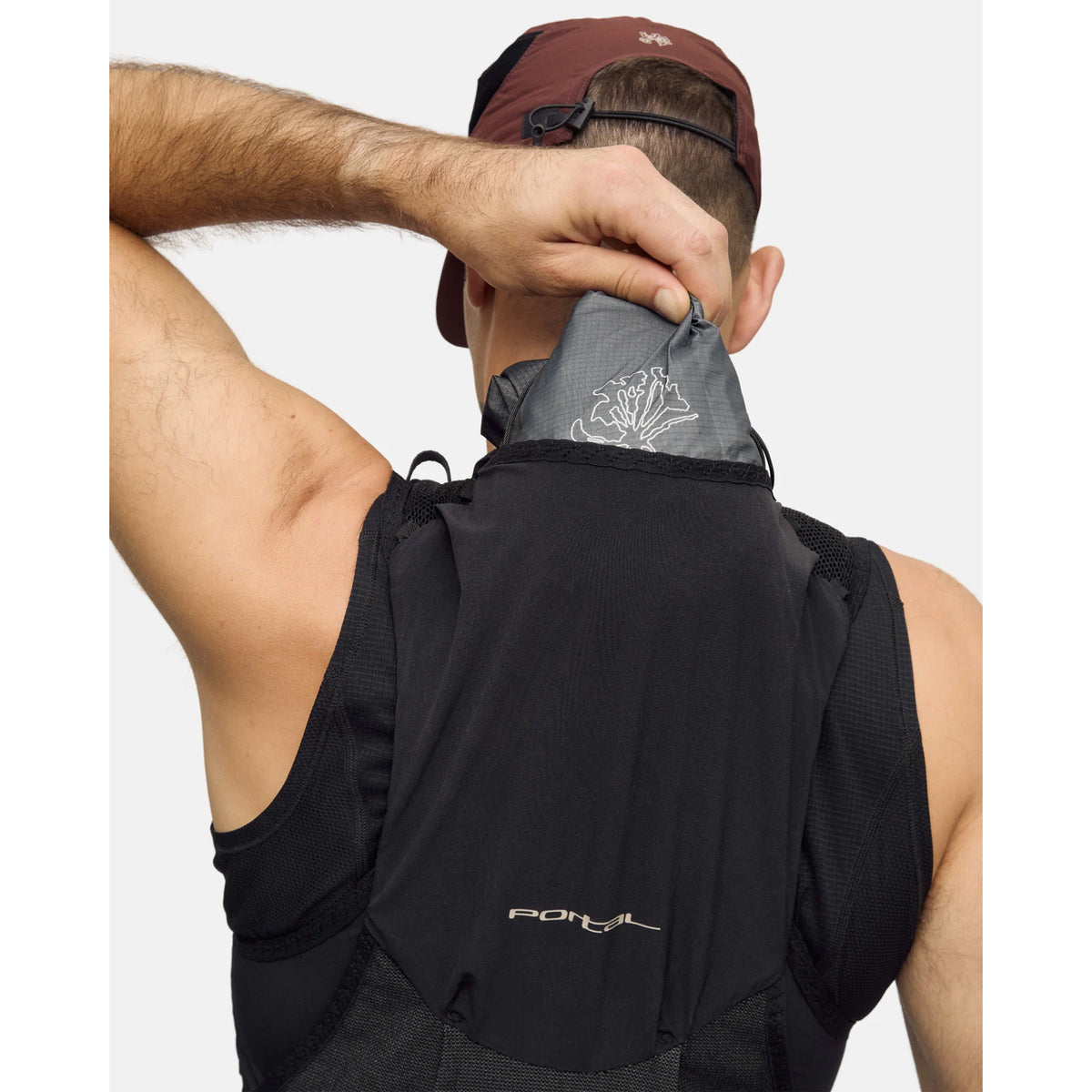 A person wearing the Portal Passage Cargo Vest in Black Beauty pulls up a gray collar with a white mountain logo, with only their back and part of an arm visible.