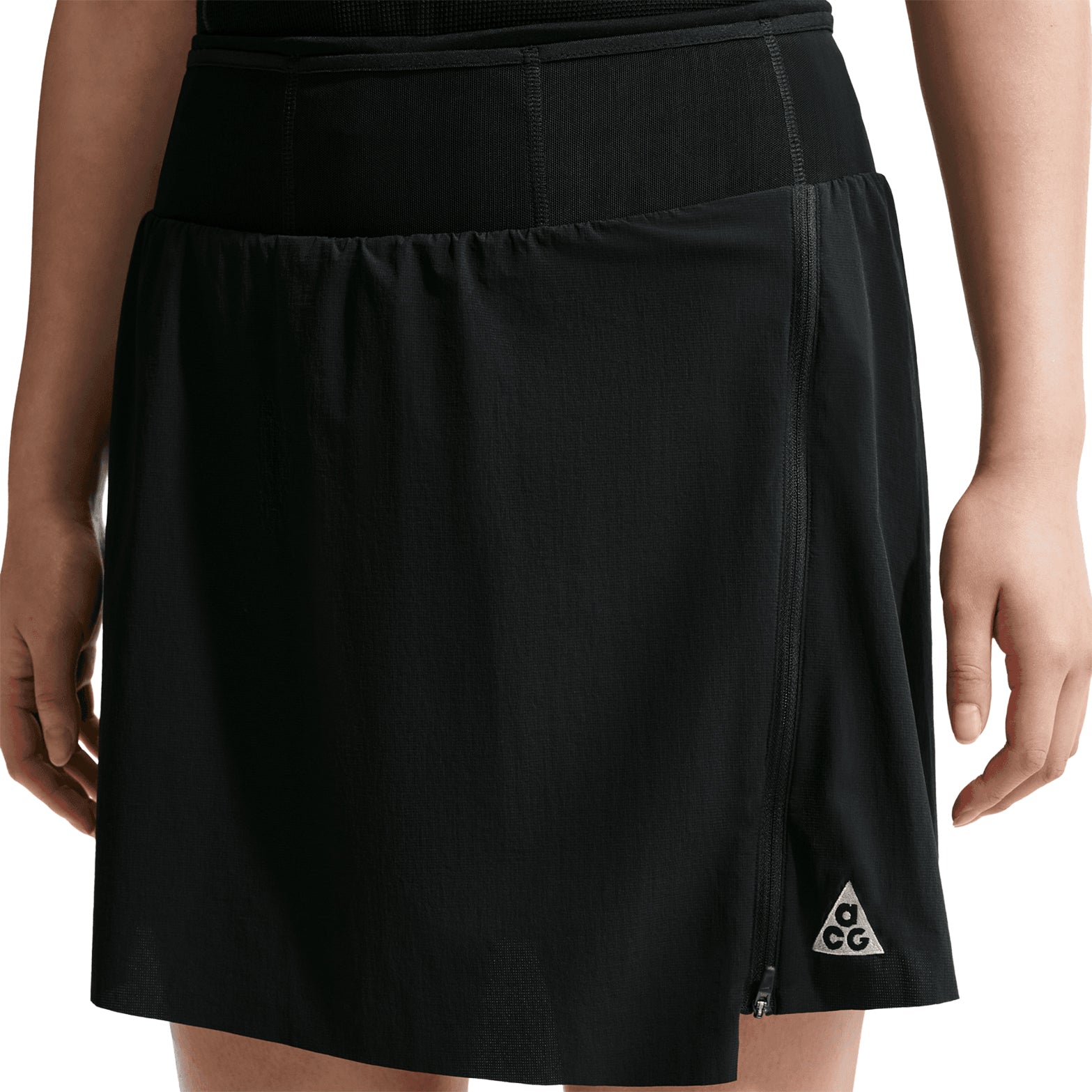 Women's Nike ACG High Stakes Skort Black Black Summit White front view on female trail runner showing stretch-woven outer with wide stretchy waistband and built-in knit shorts for comfortable hiking
