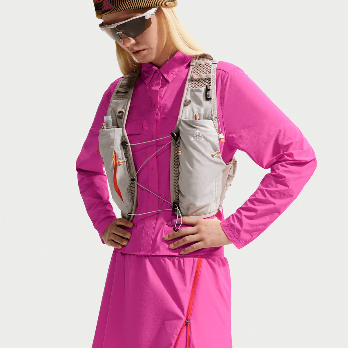 Women's Nike ACG High Stakes Skort Desert Pink Light Crimson Summit White front view on female trail runner showing stretch-woven outer with wide stretchy waistband and built-in knit shorts for comfortable hiking