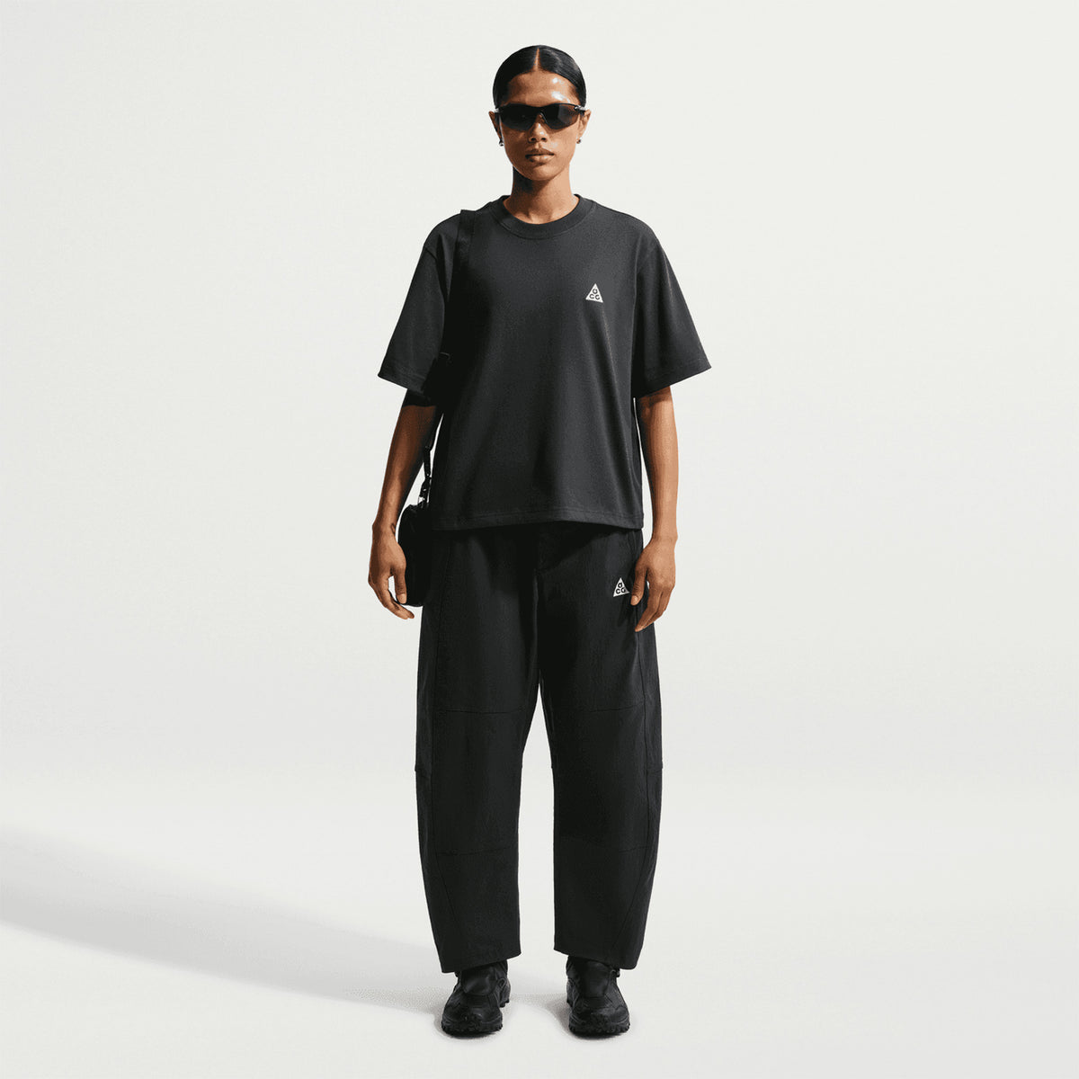 Nike ACG Tee women's in Black / Summit White — full body front view worn on model showing black loose-fit knit tee with summit white detailing, unrestricted silhouette and sustainable material construction