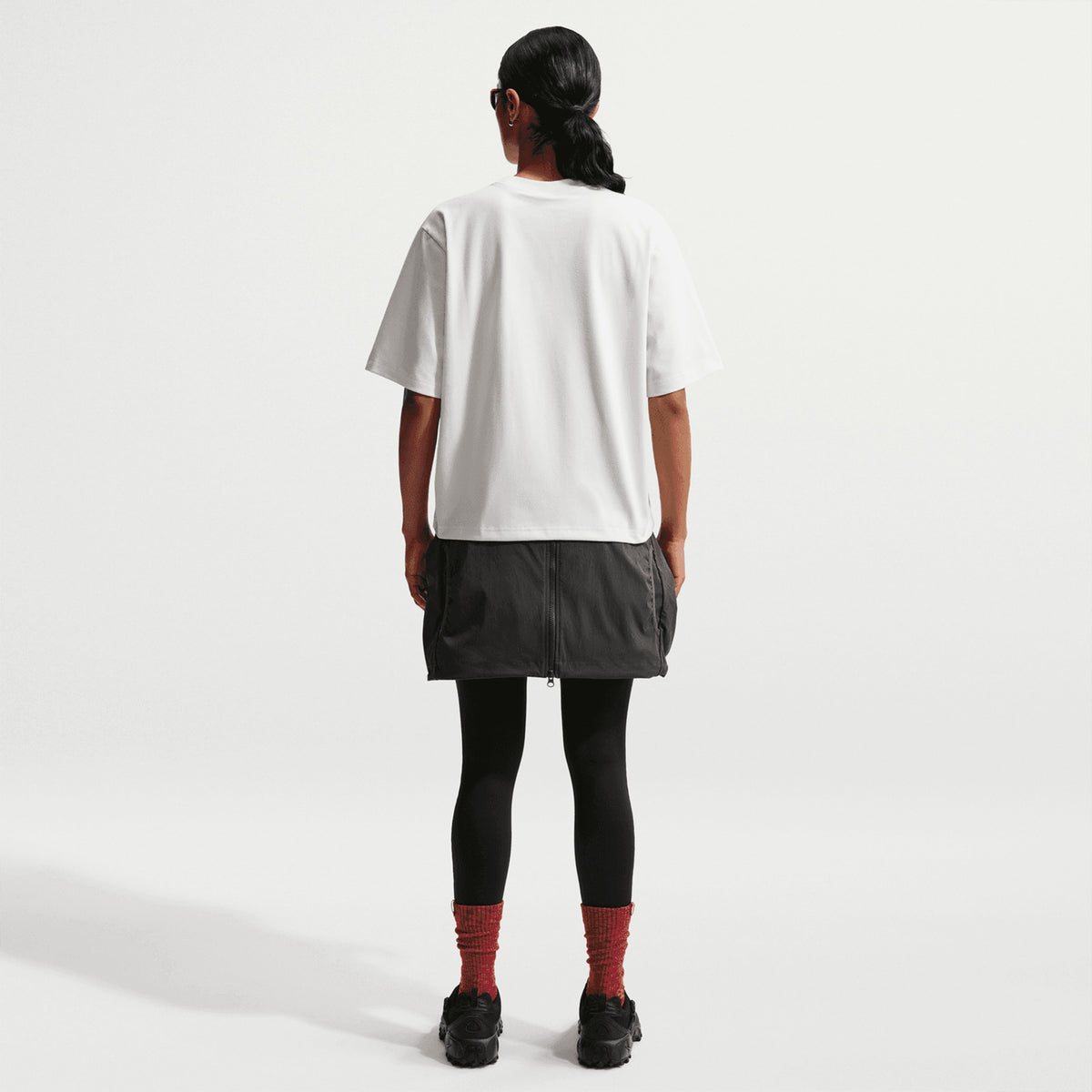 Nike ACG Tee women's in Summit White / Black — full body back view worn on model showing summit white loose-fit knit tee with black accent detailing and generous roomy cut for outdoor readiness