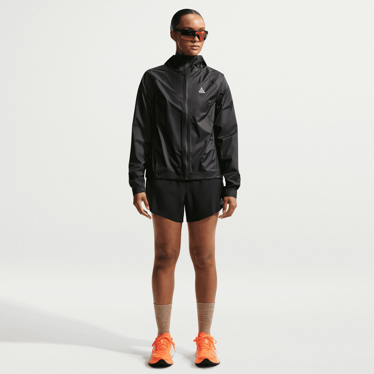 Women's Nike ACG Trailwind Storm-FIT ADV Jacket Black Summit White full body view on female trail runner showing ultra-lightweight Storm-FIT ADV waterproof construction with bungee-adjustable hood for unpredictable trail conditions