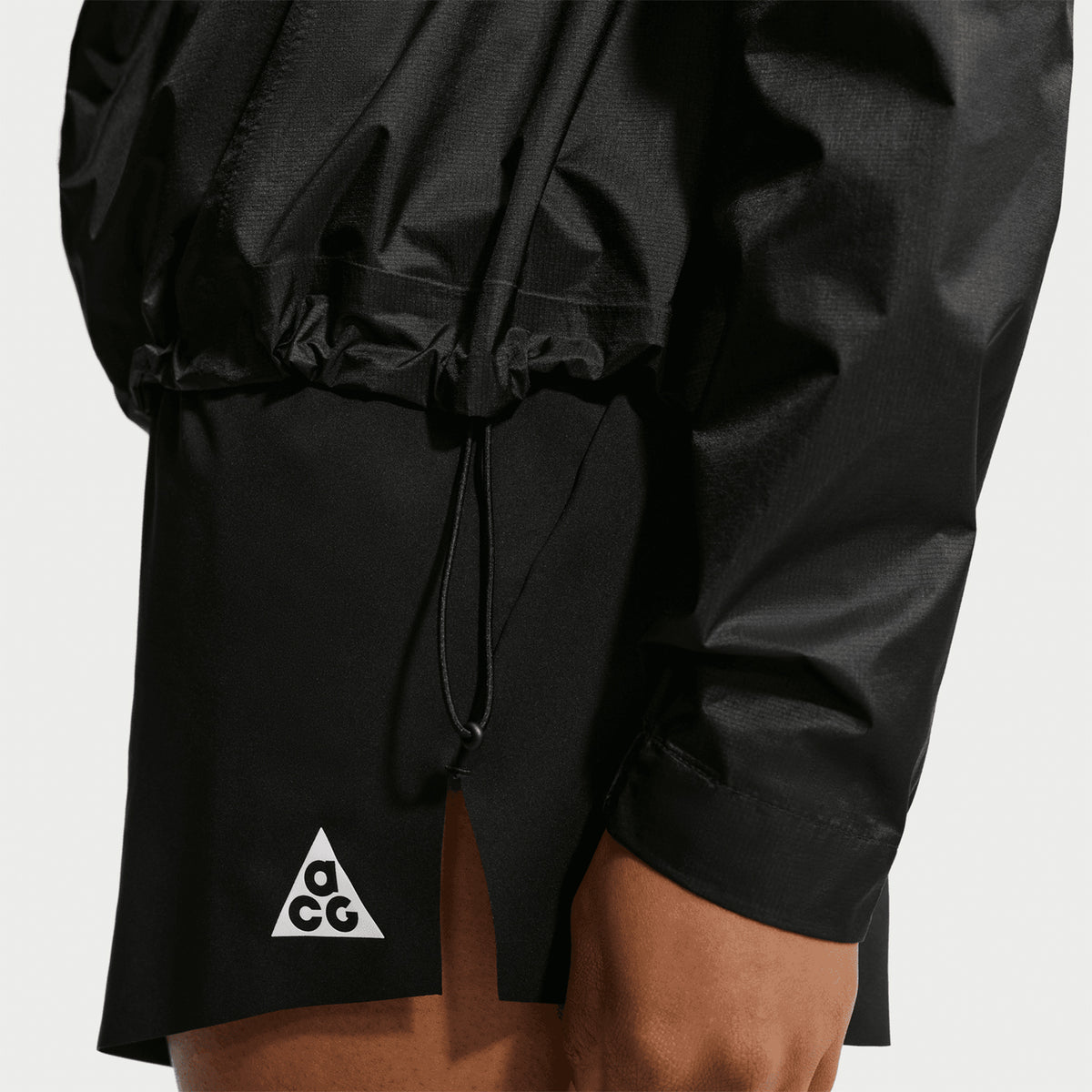 Women's Nike ACG Trailwind Storm-FIT ADV Jacket Black Summit White side view on female trail runner showing packable lightweight construction with back vents and sealed seams for all-conditions trail running