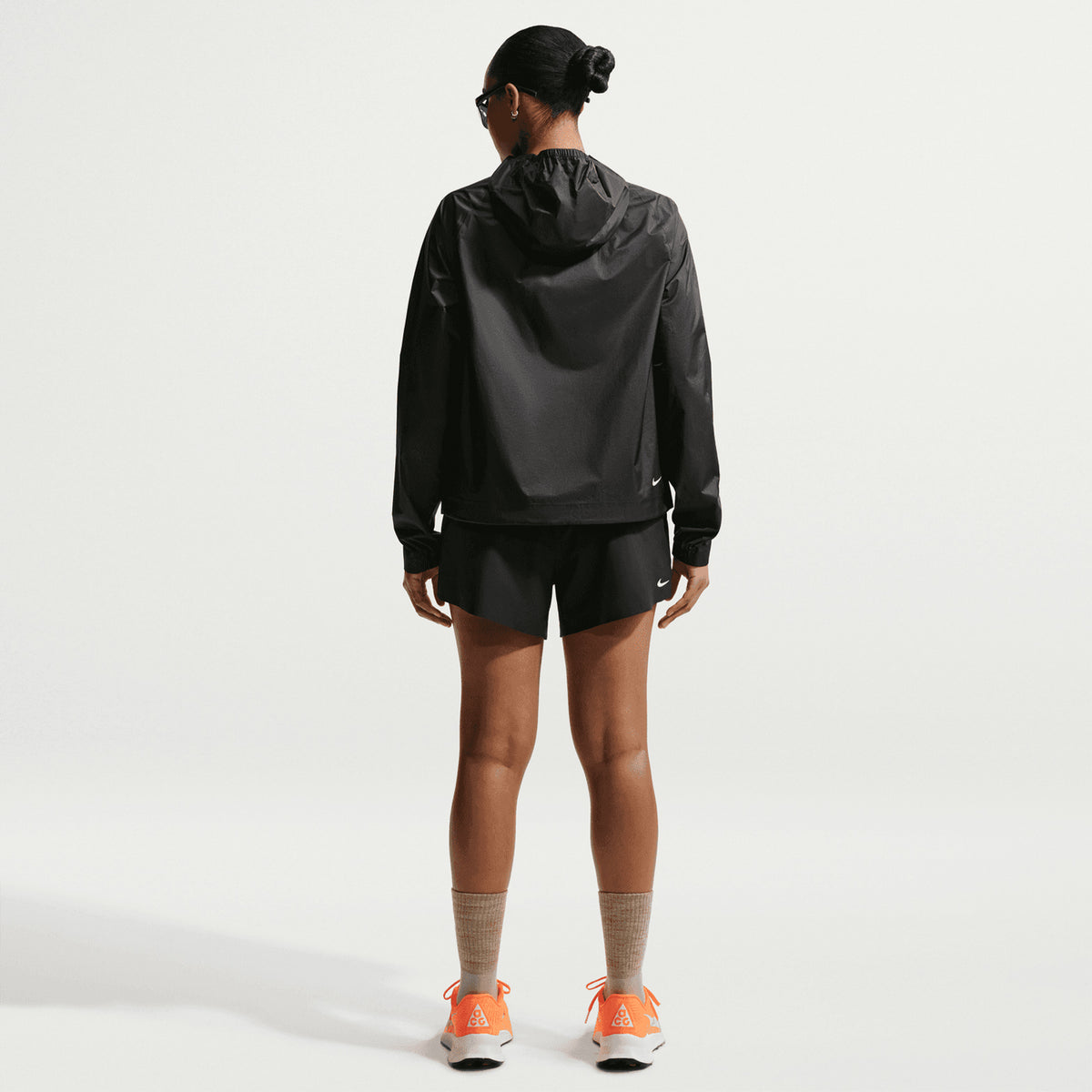 Women's Nike ACG Trailwind Storm-FIT ADV Jacket Black Summit White full body back view on female trail runner showing back vents with Storm-FIT ADV waterproof nylon and reflective ACG branding for breathable weather-protected trail running