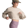 A person wearing the Women’s Adi365 H.Koumori Running Crew Top in Putty Grey by Adidas, paired with mauve leggings and a tan cap, stands in a running pose against a white background—a look inspired by the Adidas Running Crew’s streetwear-infused crewneck style.