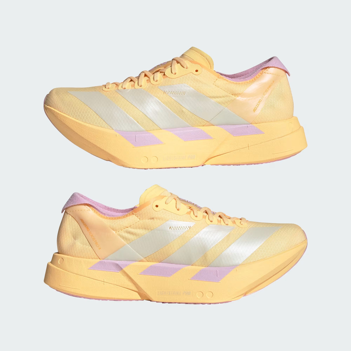 Two yellow running shoes with white stripes, pink accents on the heel, and light purple details on the sole, shown side by side on a plain light background.