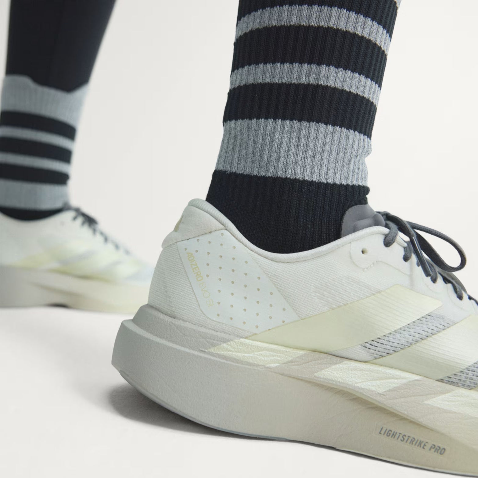 Women's adidas Adizero EVO SL Running Shoes Off White Ice Gold Metallic Granite angled side and heel view showing LIGHTSTRIKE PRO foam midsole with Continental rubber outsole and racing-inspired aesthetic for speed training and everyday wear