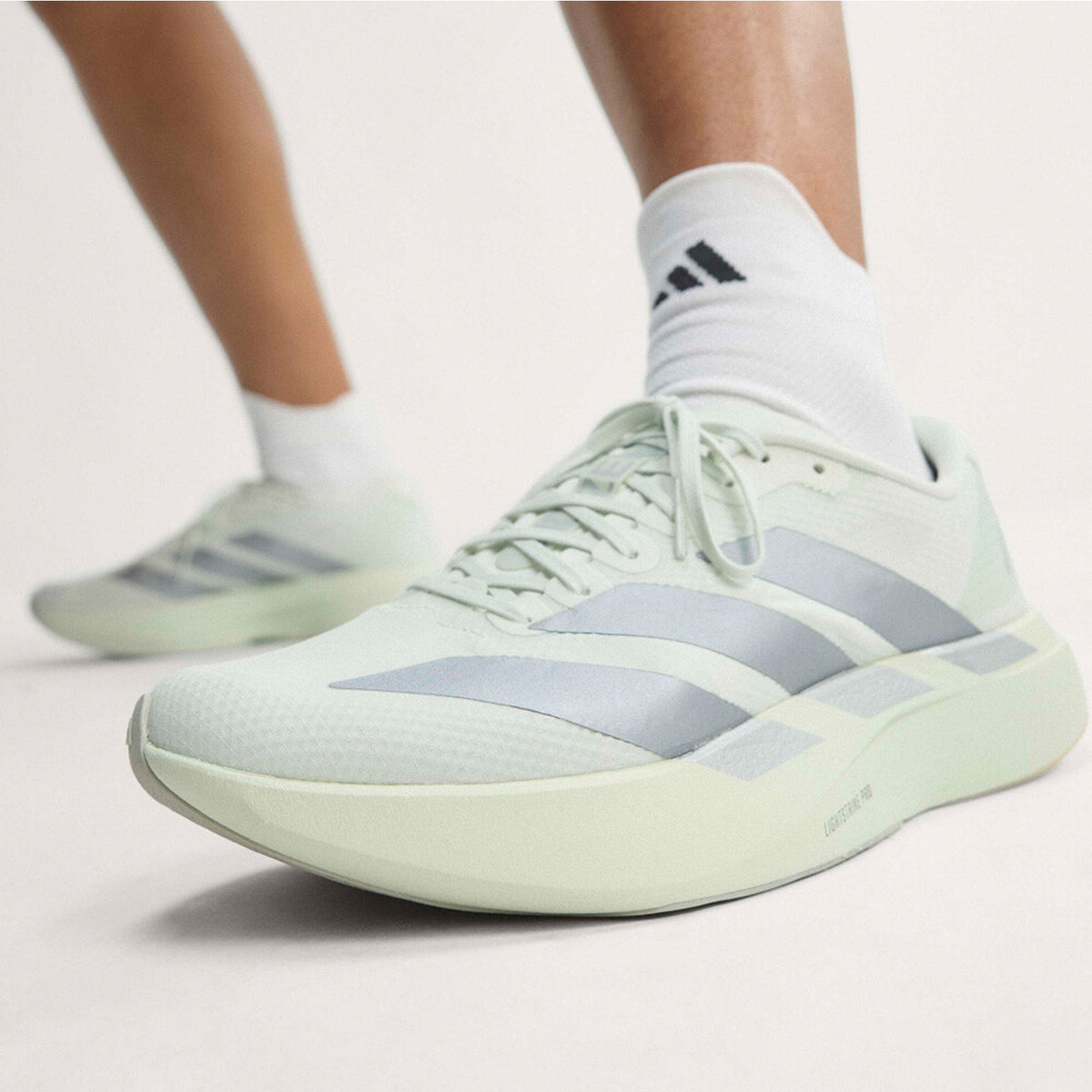 Women's adidas Adizero EVO SL Woven Running Shoes Crystal Jade Tech Grey Metallic Wonder Silver side view on female runner showing woven racing-inspired design with LIGHTSTRIKE PRO foam for running performance and lifestyle versatility