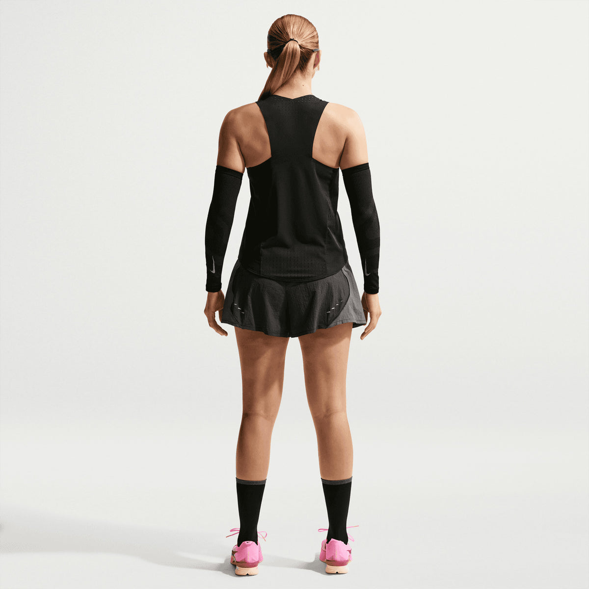 Nike AeroSwift Dri-FIT ADV Women's Running Vest in Black / White — full body back view worn on model showing pleated back detail, side slit airflow construction and black Dri-FIT ADV fabric