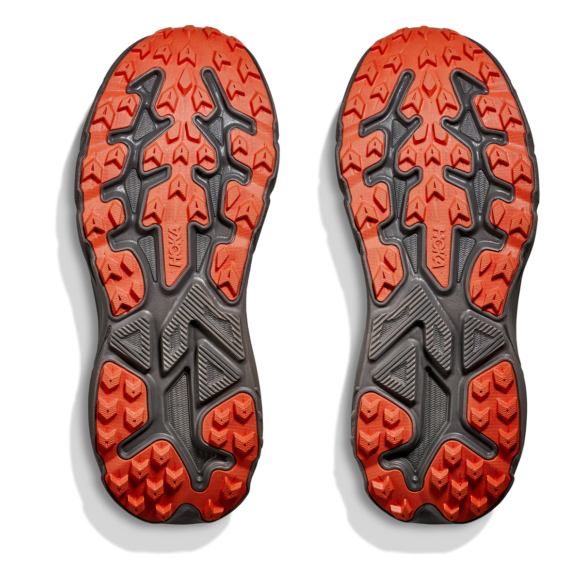 Two rugged, orange and black shoe soles with deep, multidirectional treads for enhanced traction are displayed side by side on a white background—perfect for the Hoka Women’s Challenger 8 GORE-TEX Trail Running Shoes in Cement / Gravel, designed to keep your runs cushioned and waterproof on any terrain.
