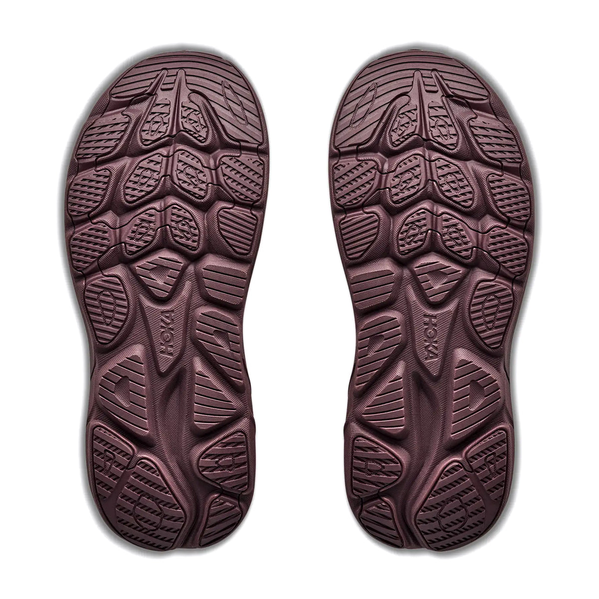 Two brown outsoles from the Hoka Women’s Clifton 11 GORE-TEX Running Shoes in Smoky Quartz / Deep Mauve are displayed side by side on a white background. Featuring geometric tread patterns with a mix of curved and angular grooves, these waterproof running shoe soles are designed to enhance traction.