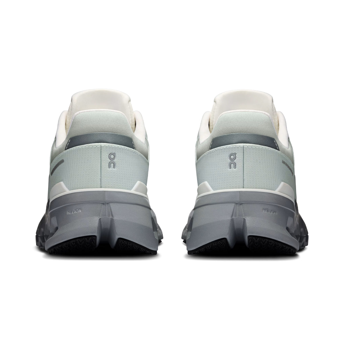 A pair of Women’s Cloudrunner 2 Waterproof Running Shoes by On in Iceberg / Alloy is shown from the back, highlighting the ON brand logo on each heel and a chunky, textured sole made with Helion™ superfoam. This waterproof design delivers comfort and performance, making it an ideal running shoe for all conditions.