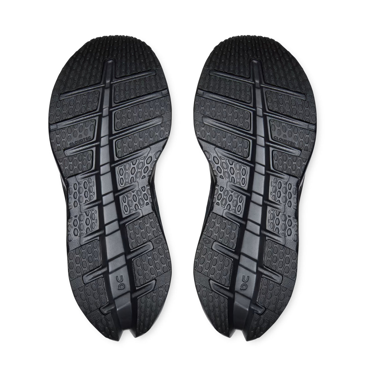 Two black rubber outsoles from the On Women’s Cloudrunner 3 Waterproof Running Shoes in Black / Black are displayed side by side, showcasing textured tread patterns with circular, rectangular, and wavy grip designs against a white background.